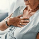 An older woman with GERD holds her chest
