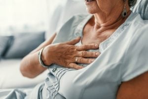 An older woman with GERD holds her chest