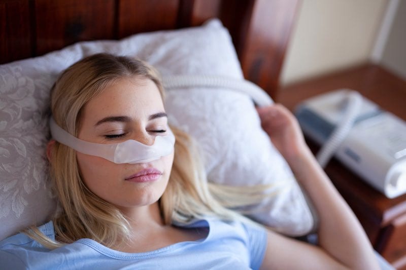 Woman sleeping with CPAP mask under nose