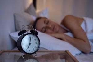 Woman sleeping in bed with a clock on the nightstand