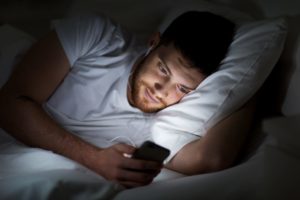 man in bed looking at his phone