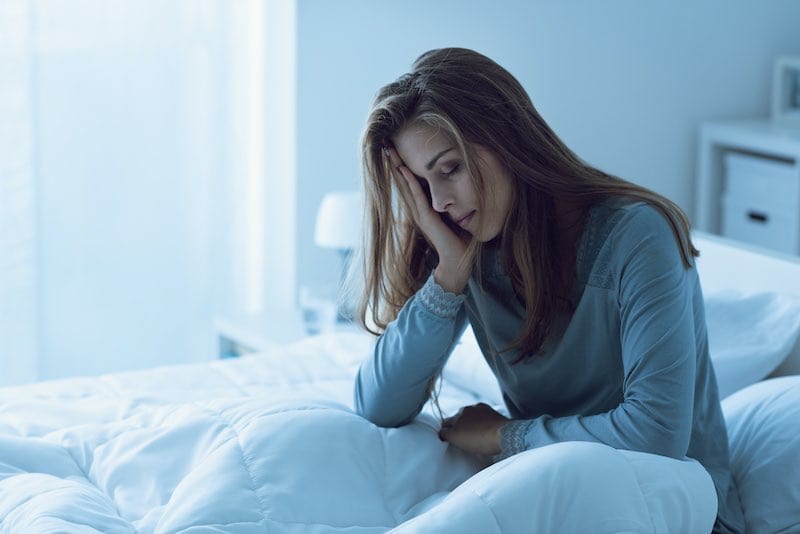 Woman seated in bed suffering from insomnia