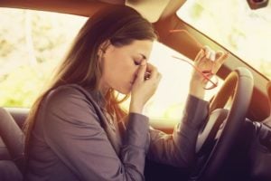 Woman in drivers seat rubbing eyes