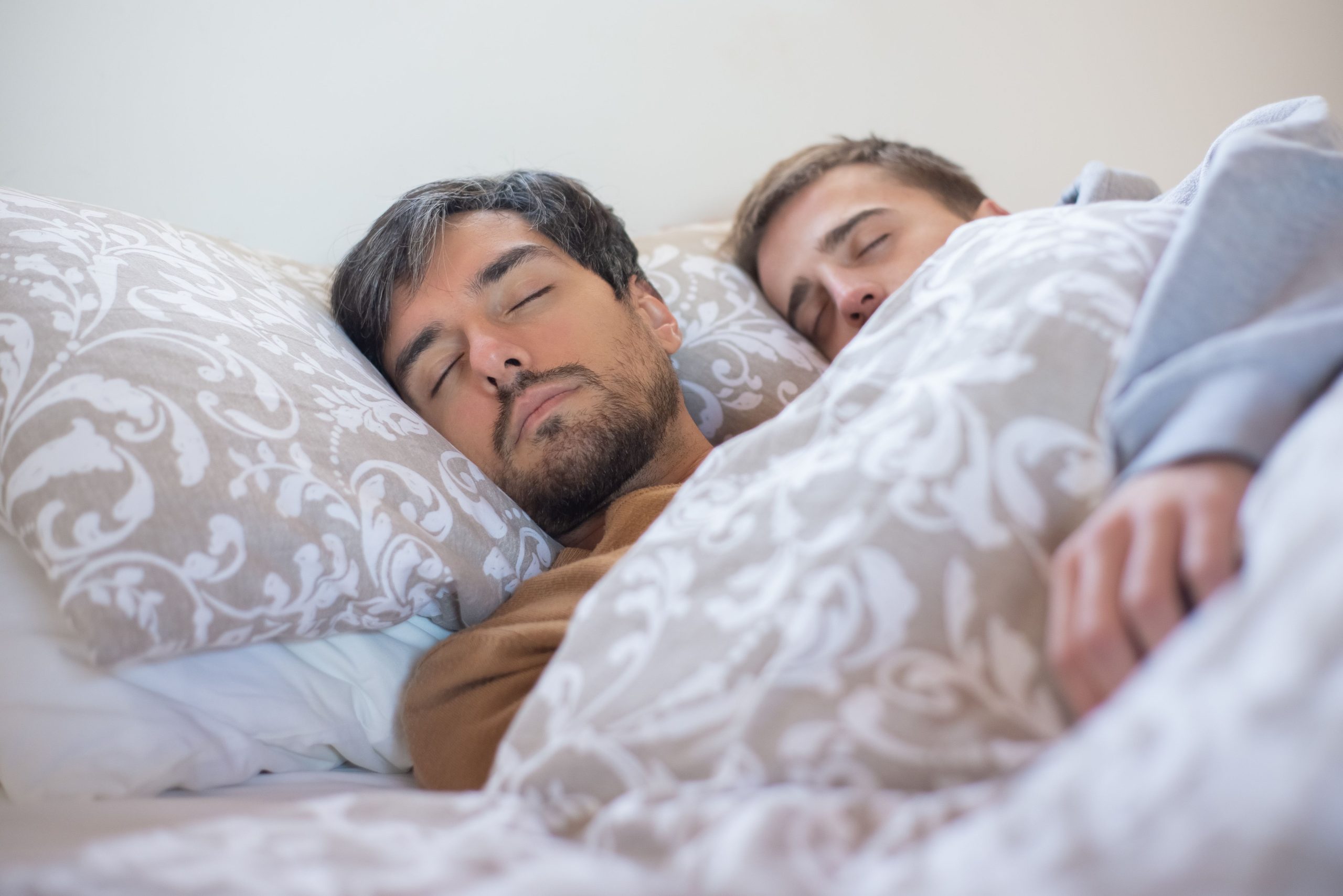 Sleep and Memory A loving couple peacefully sleeping together, embracing under a warm blanket indoors.