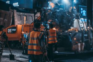 Shift Work Workers in safety vests operate heavy machinery at a night construction site