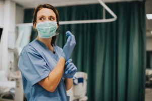 Female nurse with a mask putting on gloves