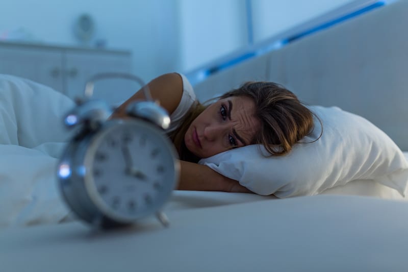 Woman with Insomnia lying in bed looking at clock Image