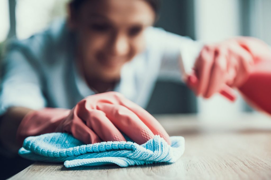 Person wearing gloves cleaning surfaces