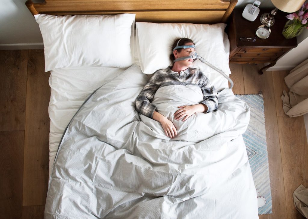 Woman sleeping bed wearing a CPAP mask