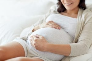 Pregnant woman holding her belly in bed