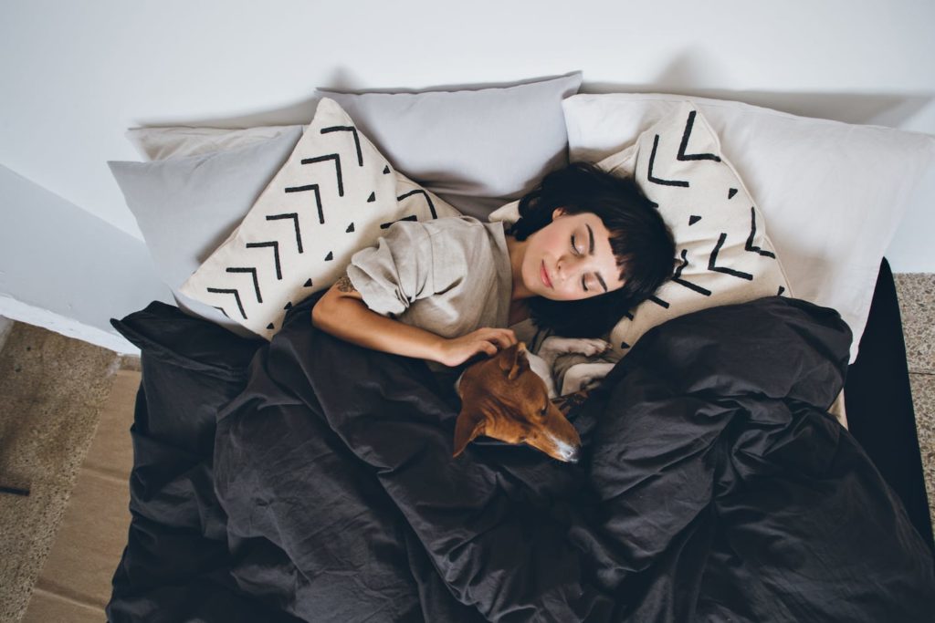 women sleeping in bed with dog