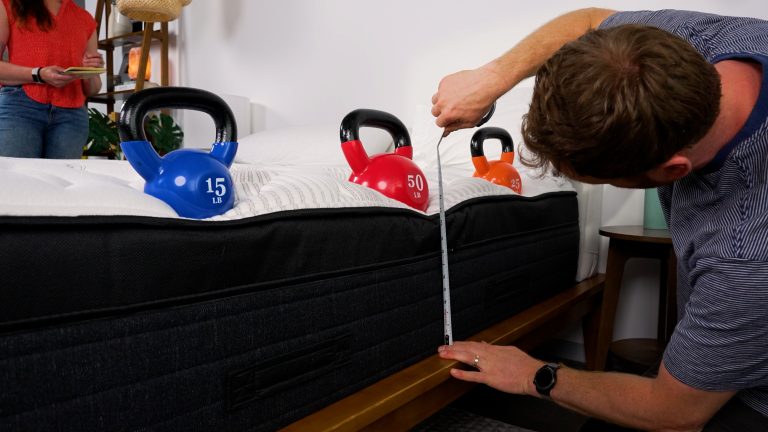 Sleep Foundation tester evaluating the Nolah Evolution mattress with a tape measure and kettlebells