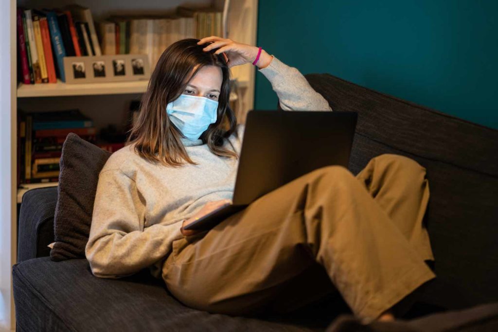 Woman wearing a mask looking at a laptop