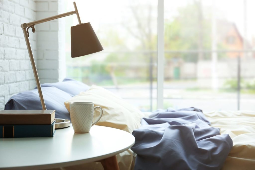 bedroom with a lamp and a cup of coffee