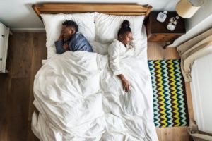 A couple in bed facing away from each other