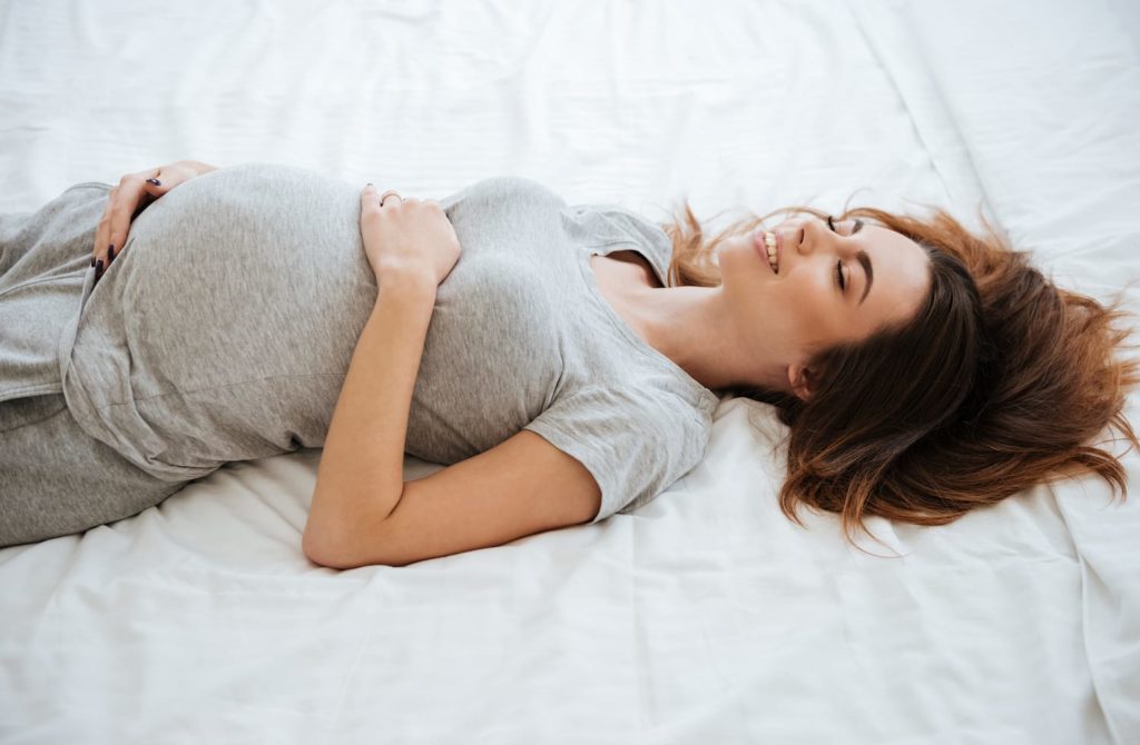 pregnant woman laying in bed smiling