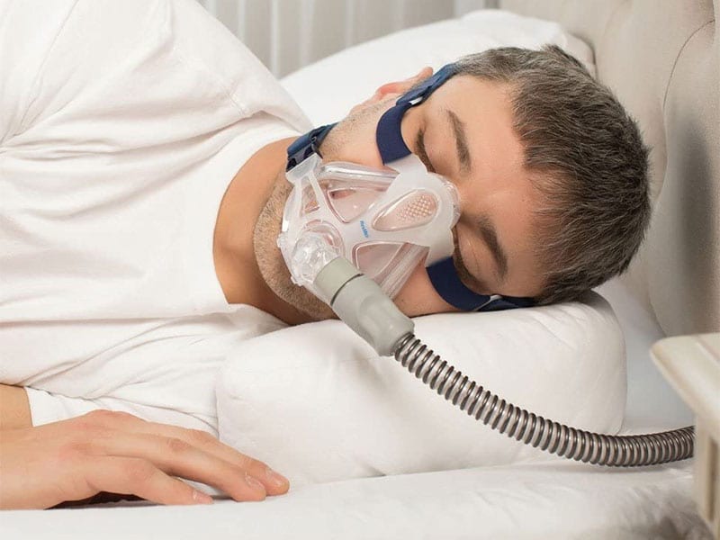 Man sleeping with pillow wearing cpap