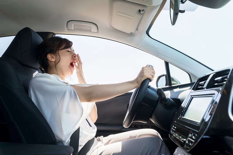 Young woman yawning in drivers seat