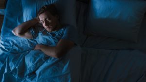 man sleeping in dark bedroom