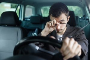 sleepy guy rubbing his eyes in the car