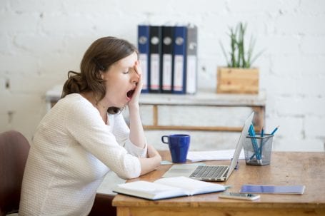 woman at desk yawning