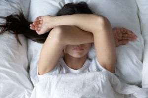 Woman laying in bed covering face