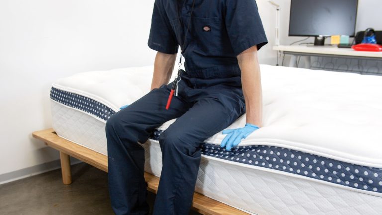 Sleep Foundation tester sitting on the edge of the WinkBed mattress to evaluate edge support