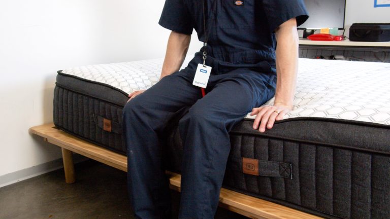 Sleep Foundation tester sitting on the edge of the Brooklyn Bedding Sedona mattress to evaluate edge support