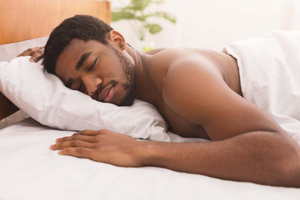A man sleeping naked on his stomach in bed.