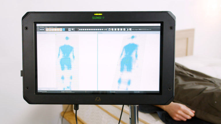 Sleep Foundation tester undergoing back-sleeping pressure mapping on the Saatva Latex Hybrid mattress