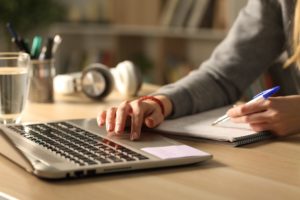 Female college student studying with laptop and notes