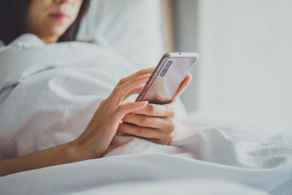 Woman looking at smart phone while in bed