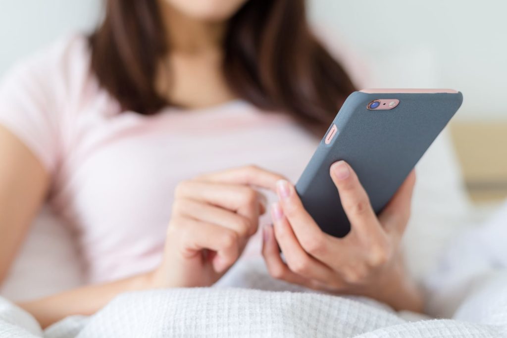 Woman using phone in bed