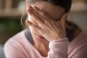 Exhausted woman holding face in hands