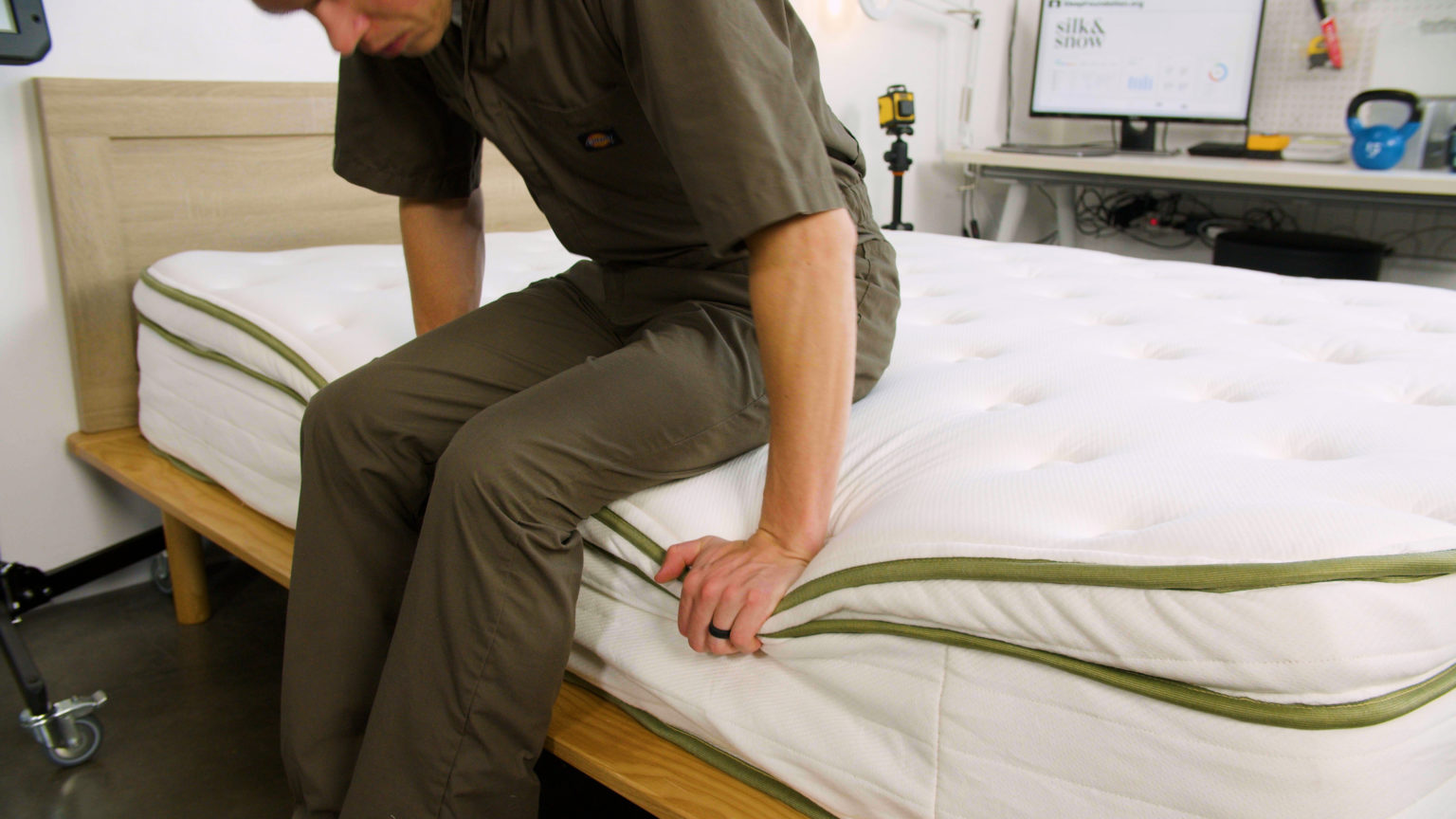 Sleep Foundation tester sitting on the Silk & Snow Organic Mattress to evaluate edge support
