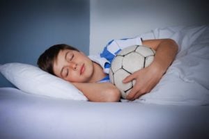 A Young boy asleep with Soccer ball