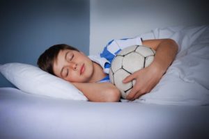 A Young boy asleep with Soccer ball