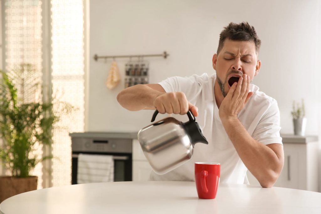 Half-awake man pouring coffee in the morning