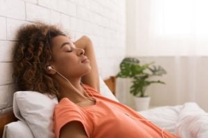 Young woman relaxing in bed with headphones
