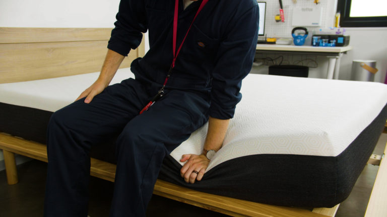 Sleep Foundation tester sitting on the Bear Original mattress to evaluate edge support