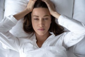 Woman lying in bed with hands on head