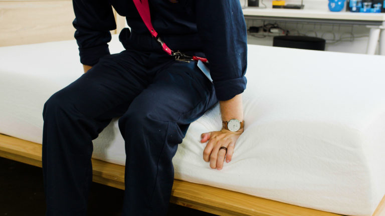 Sleep Foundation tester sitting on the Zinus Green Tea Memory Foam Mattress to evaluate edge support