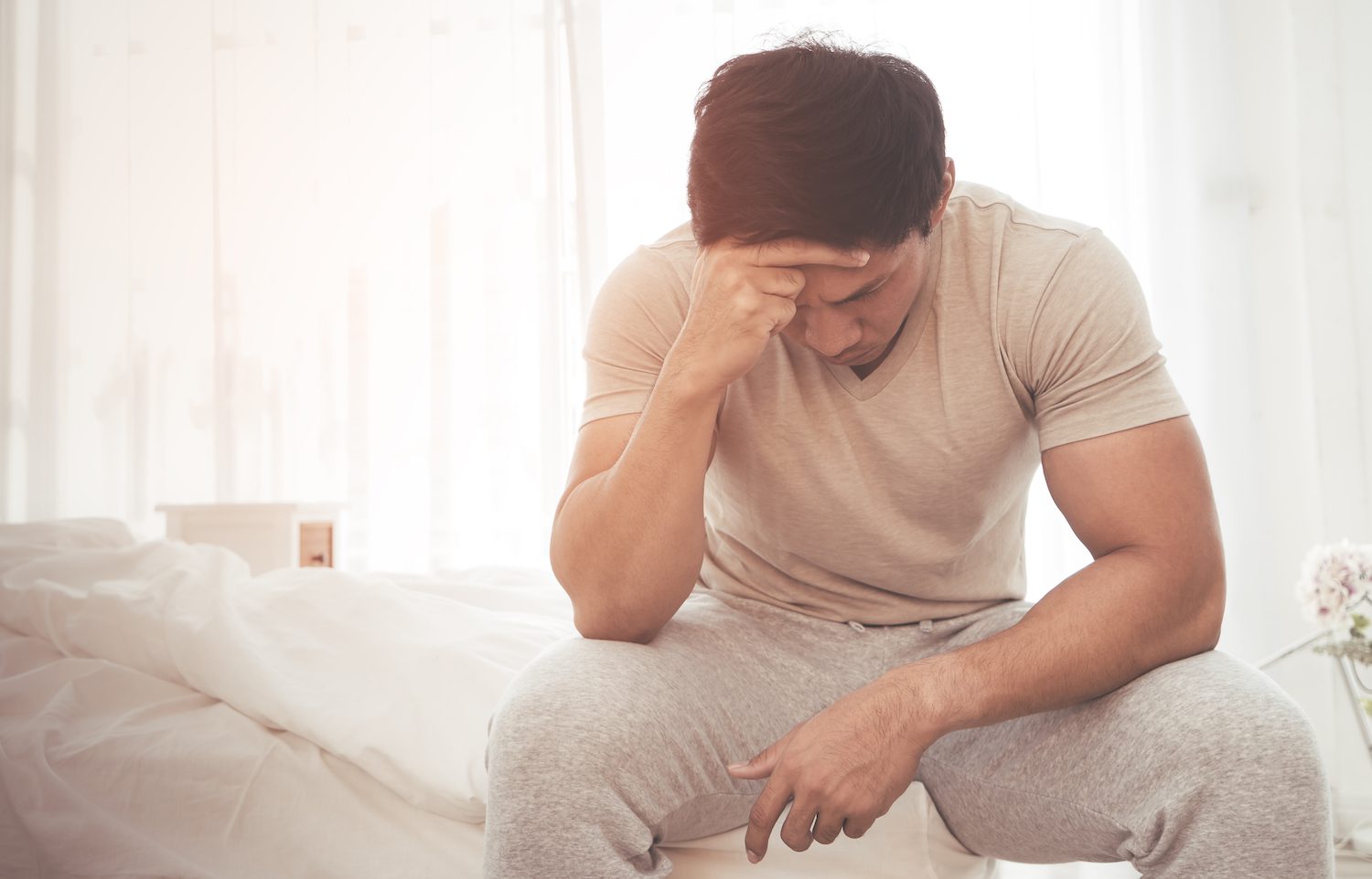Man waking up and holding head in frustration