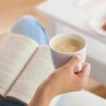Woman holding a coffee cup while reading