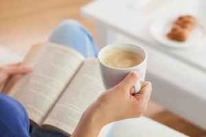 Woman holding a coffee cup while reading