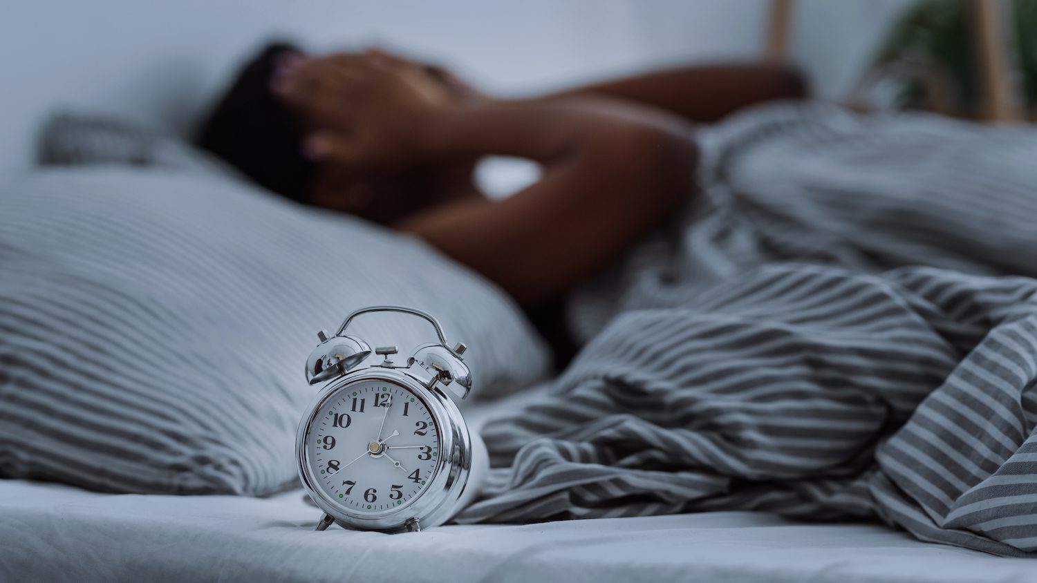 A person is waking up with a clock beside them