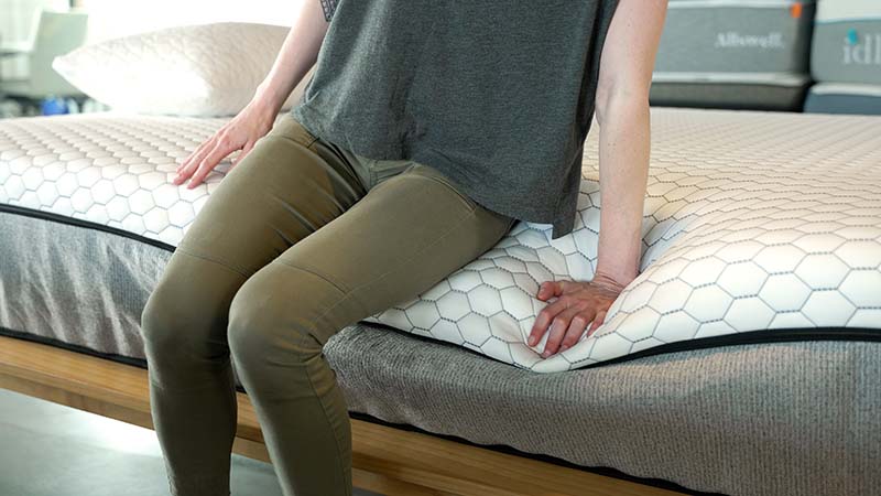 Tester sitting on the edge of a mattress