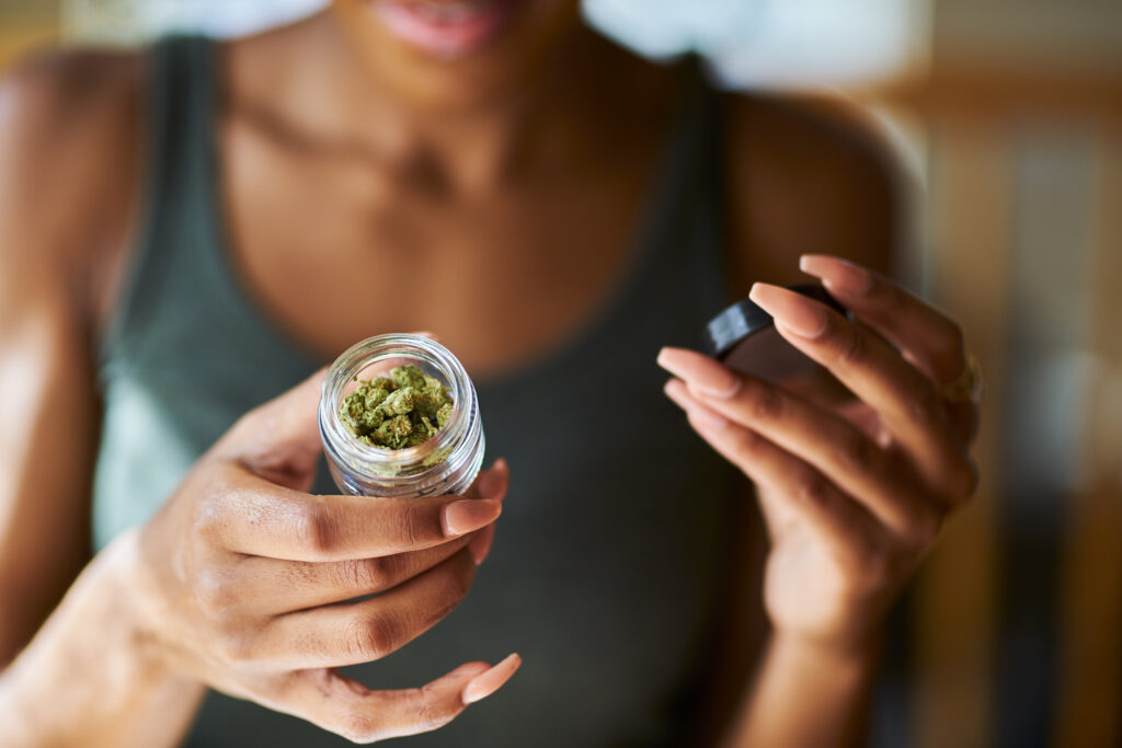 A young woman opens a container of legal cannabis from a dispensary