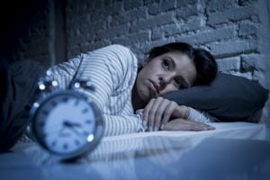 Worried woman lying in bed with eyes open