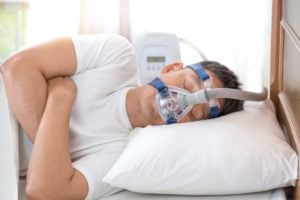 A man sleeps on his side wearing a CPAP device